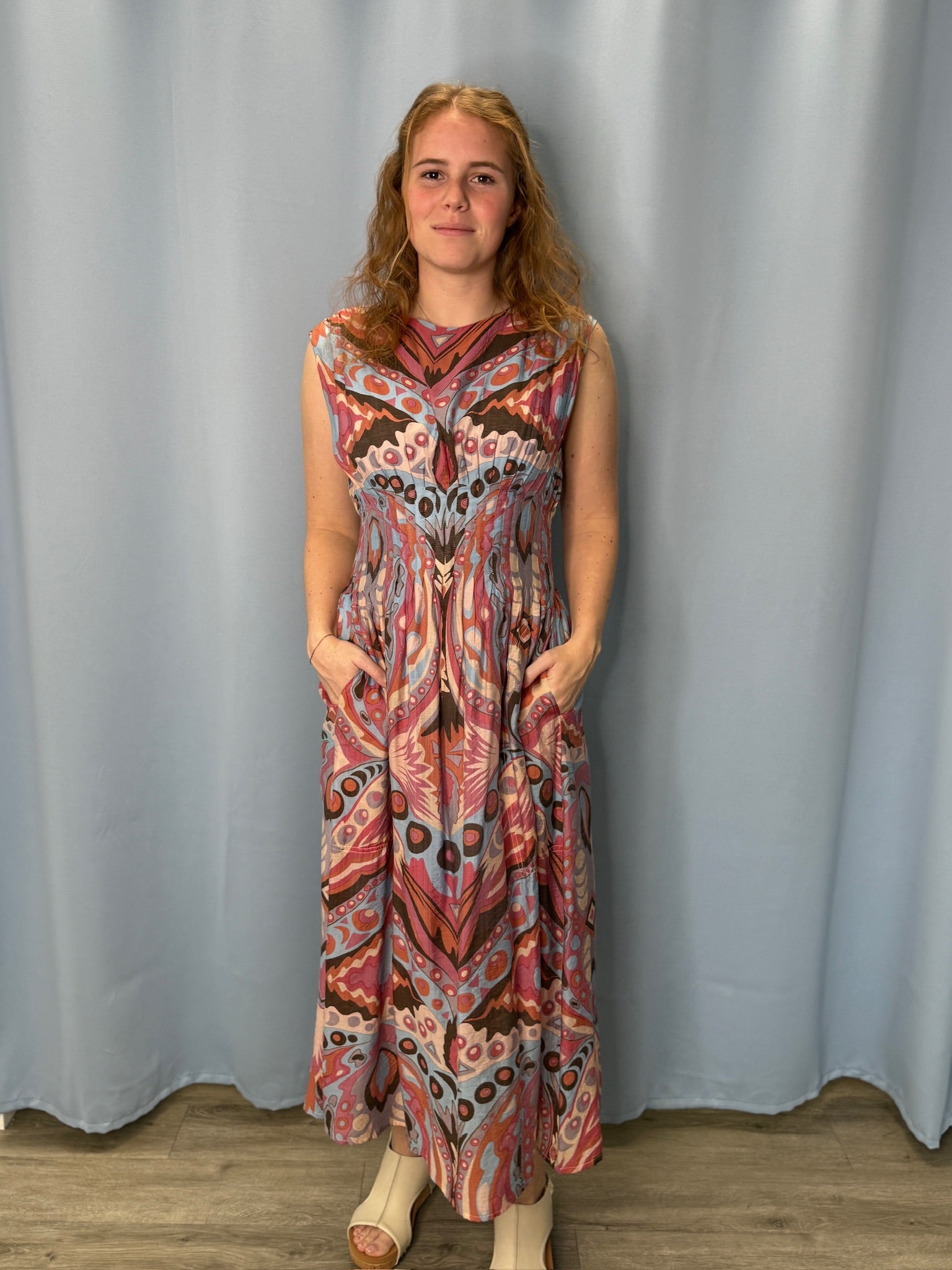 Woman wearing a patterned dress standing against a plain background