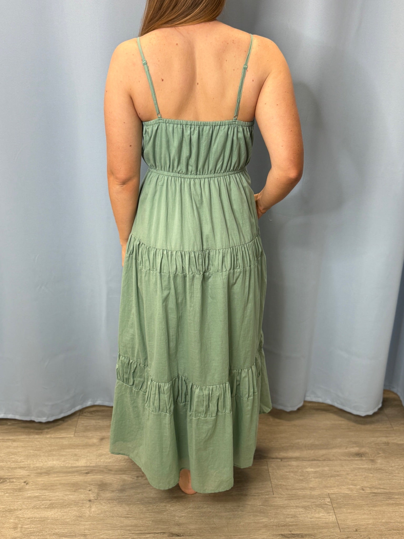 Person wearing a green dress against a plain background