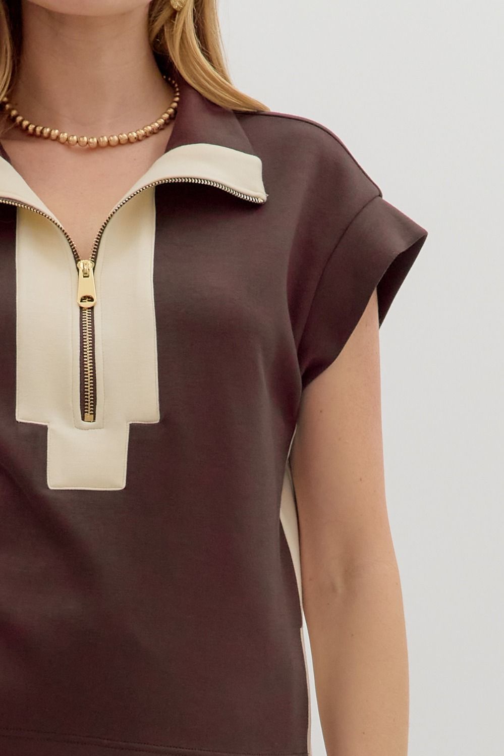 short-sleeve pullover top features a bold zip-front neckline framed with cream contrast panels