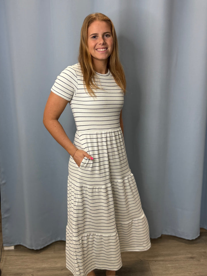 Woman wearing a striped dress standing against a plain background