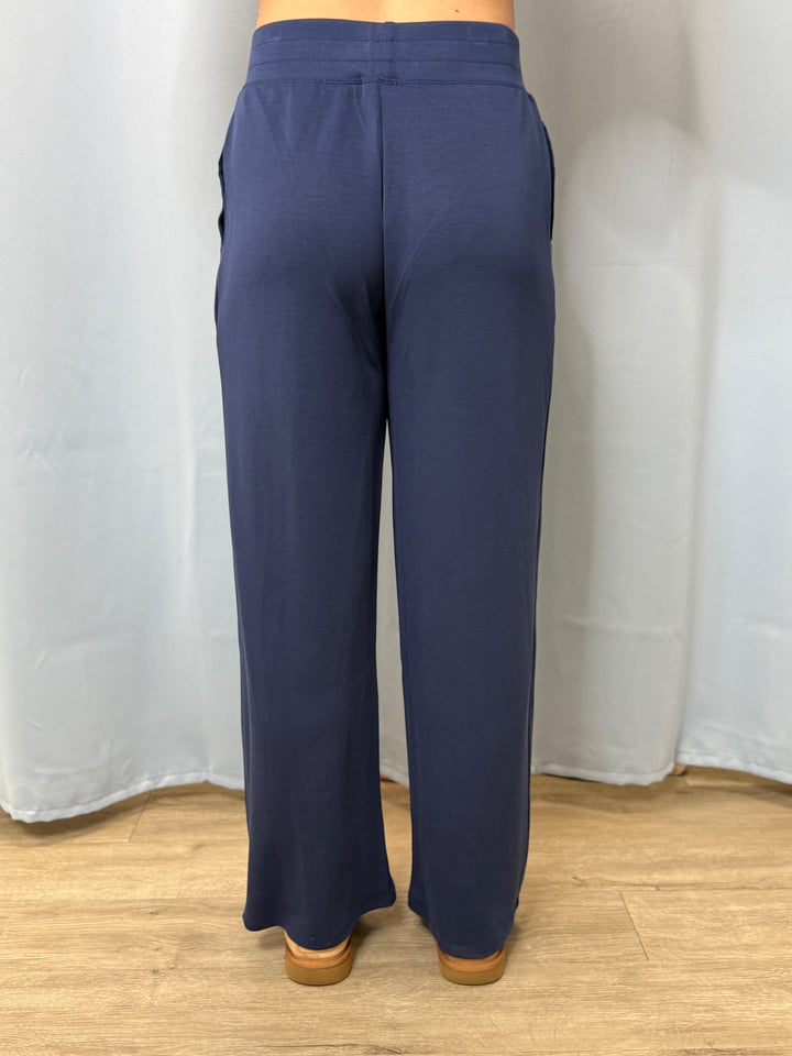 Navy blue pants worn by a person standing against a white curtain background.
