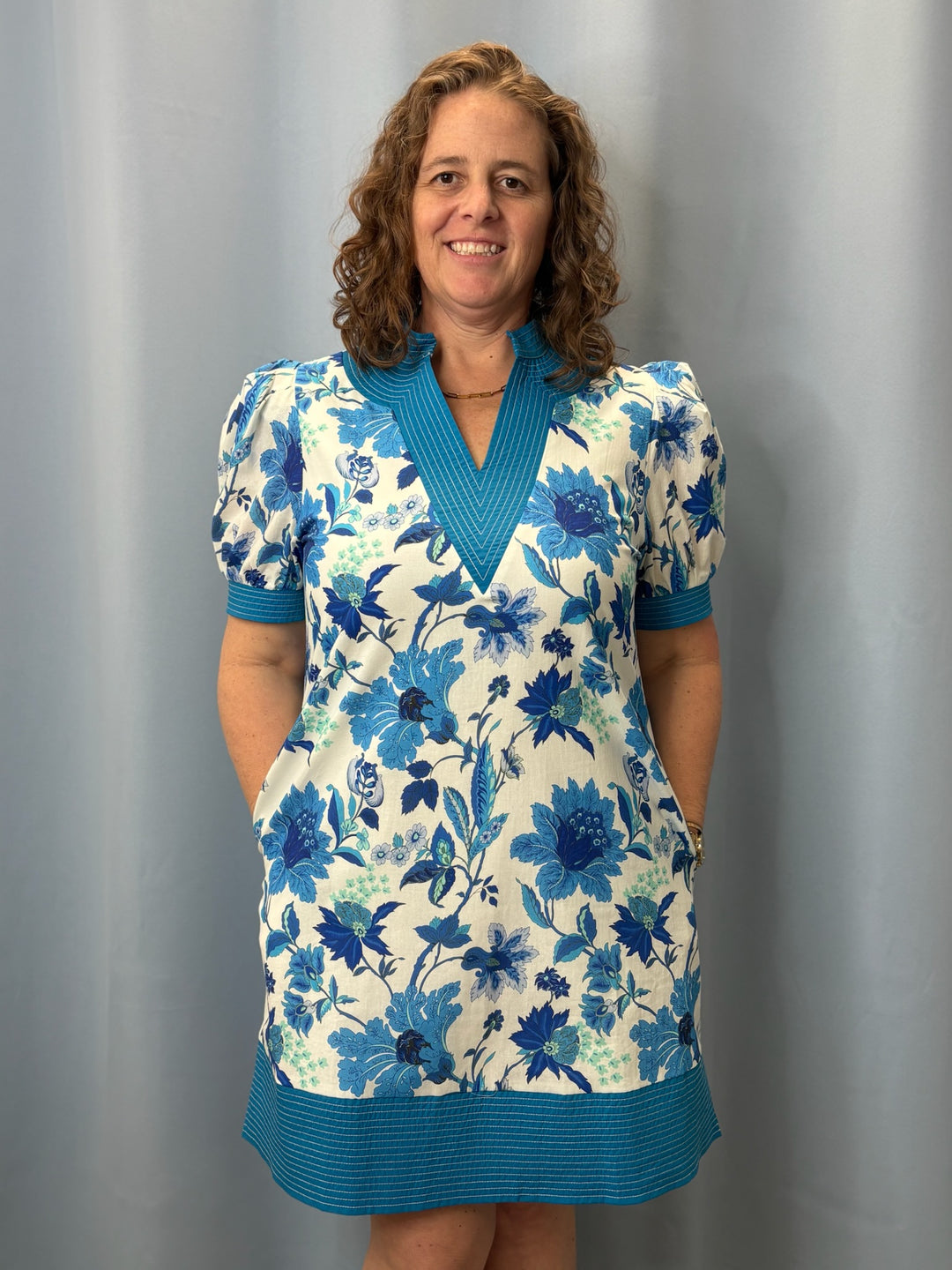Woman wearing a blue floral dress against a gray background