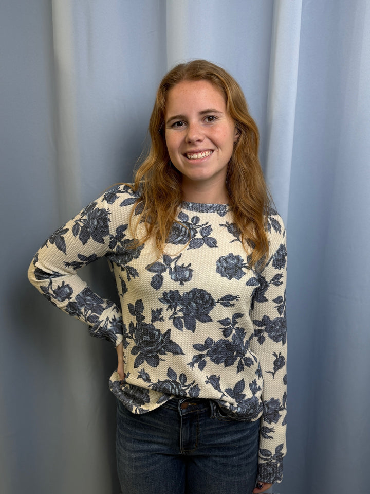 Person wearing a floral sweater against a plain background