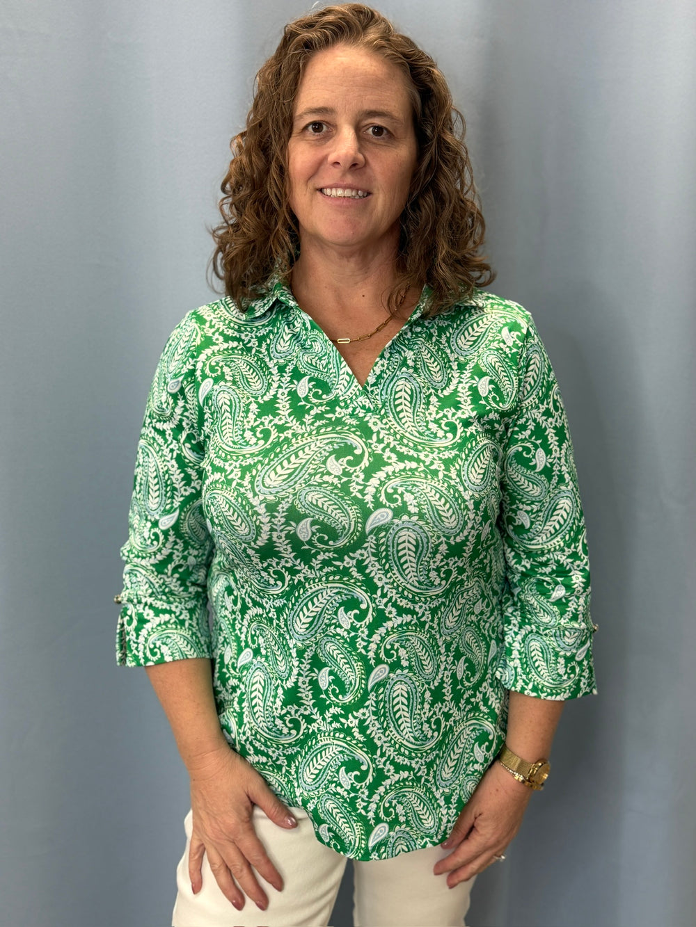 Woman wearing a green and white patterned shirt against a gray background