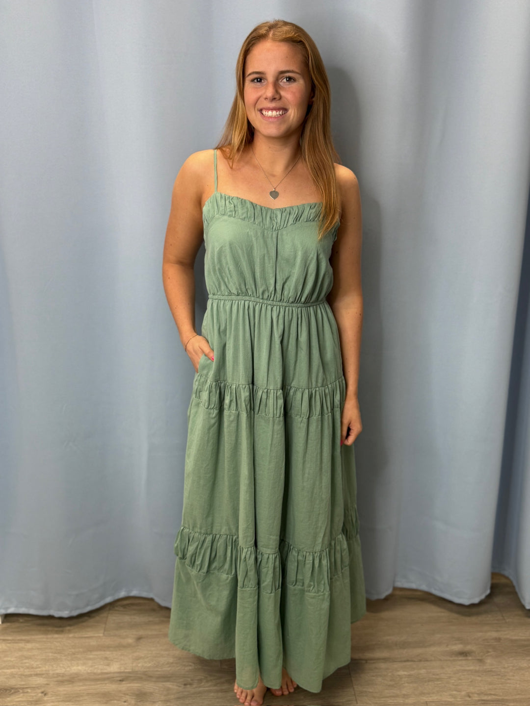 Woman wearing a green dress standing against a plain background