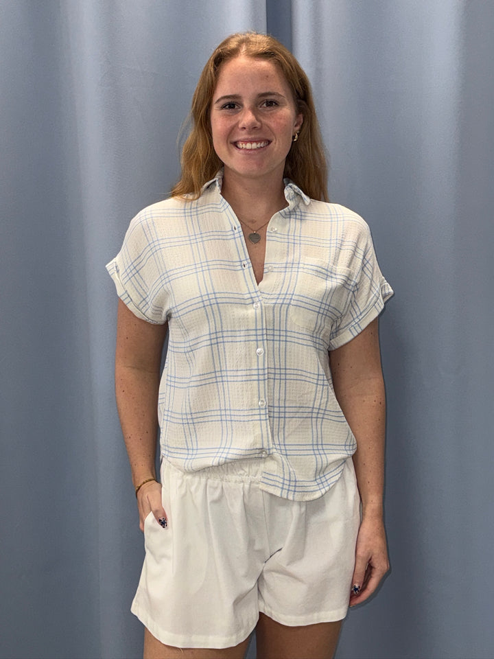 Woman wearing a plaid shirt and shorts against a plain background