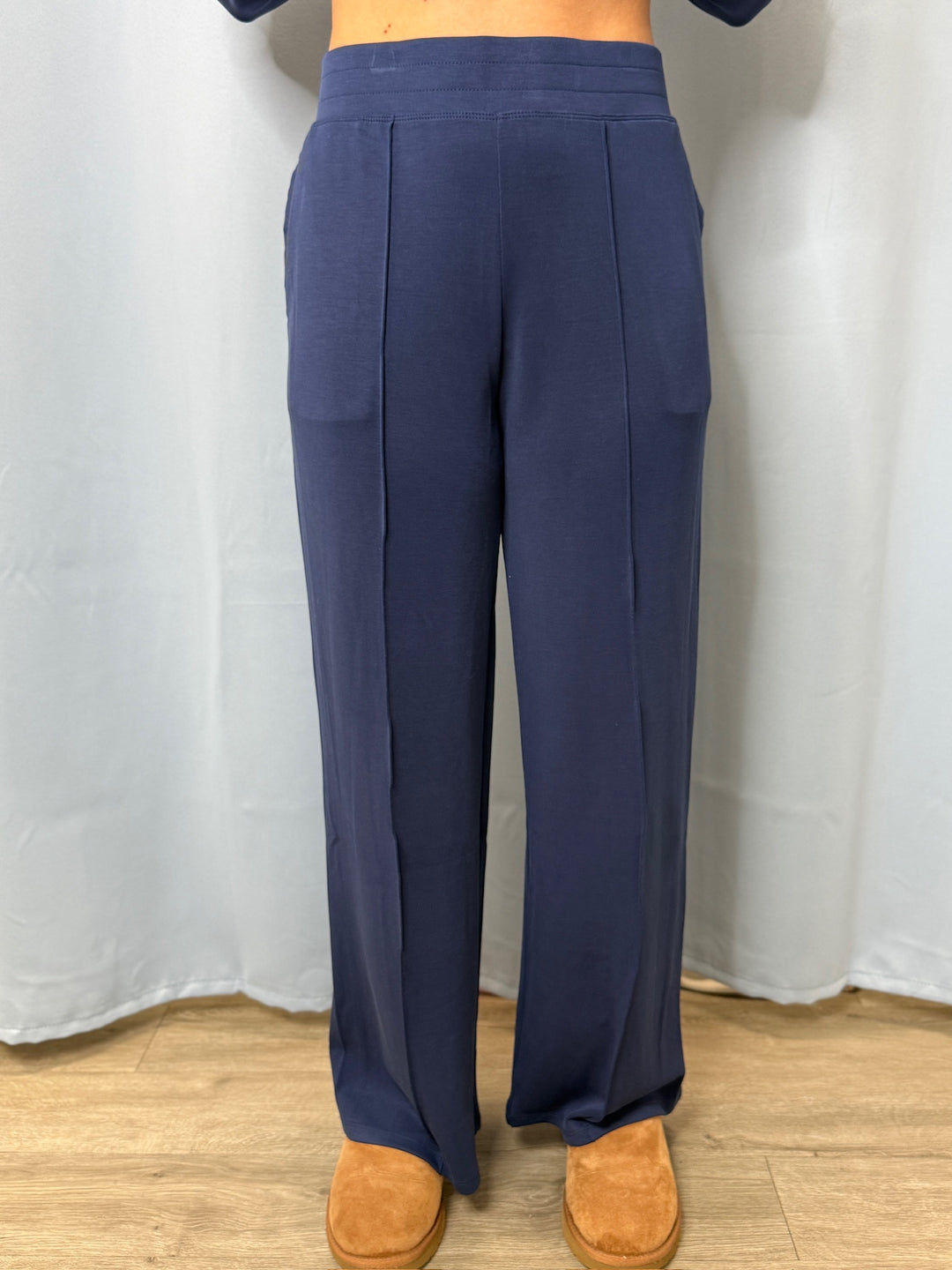 Navy blue pants worn by a person on a white background