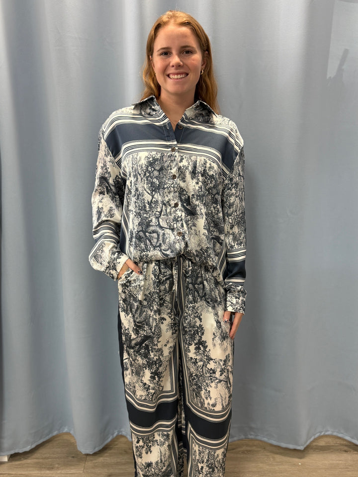 Woman wearing a patterned outfit standing against a plain background