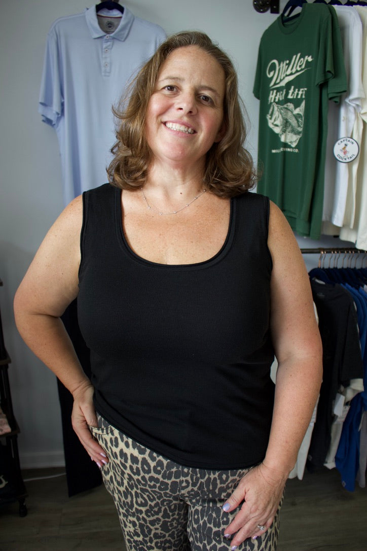 Woman wearing a black tank top and leopard print leggings standing in a clothing store.