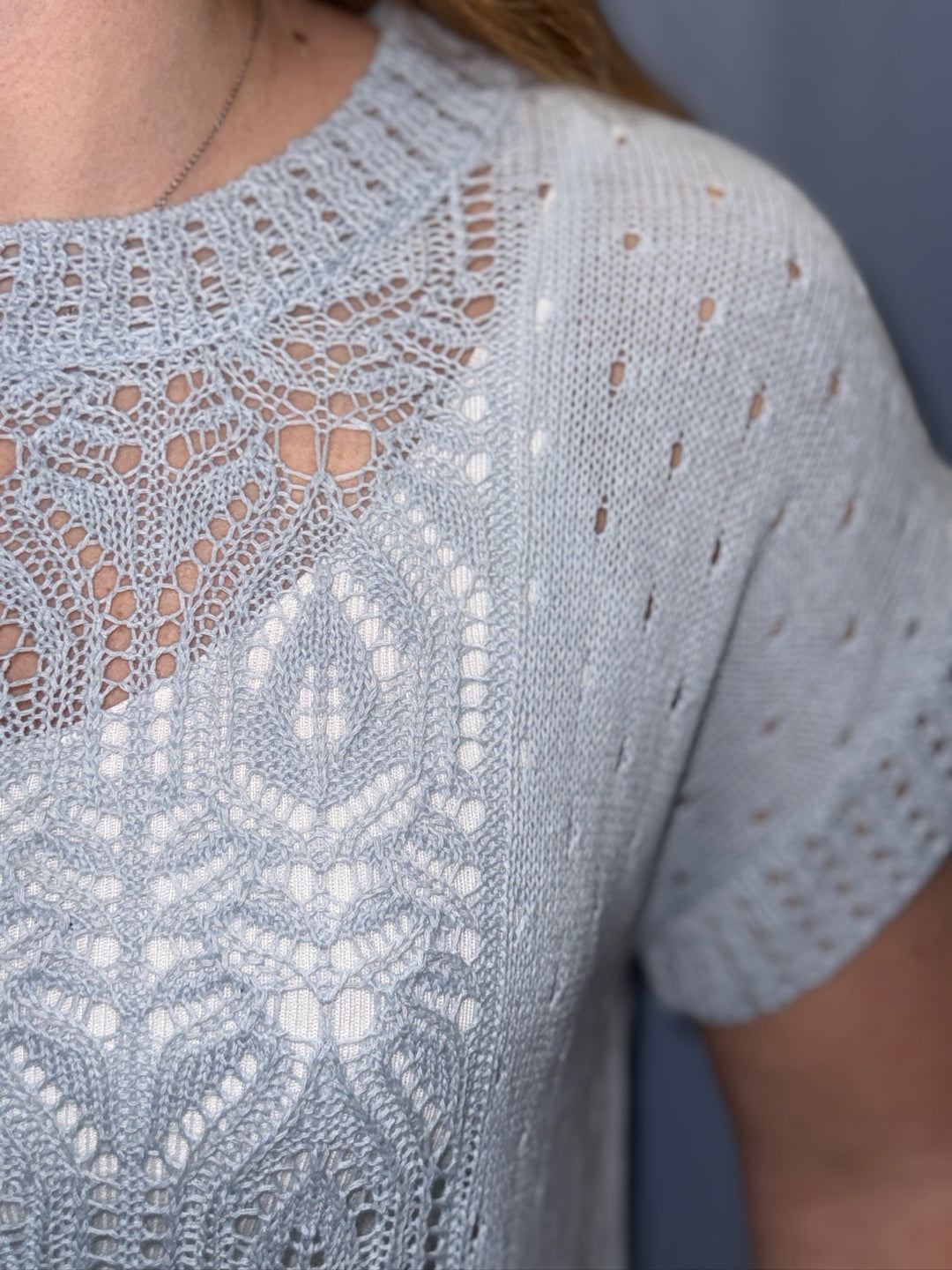 Close-up of a light blue lace top with intricate patterns.
