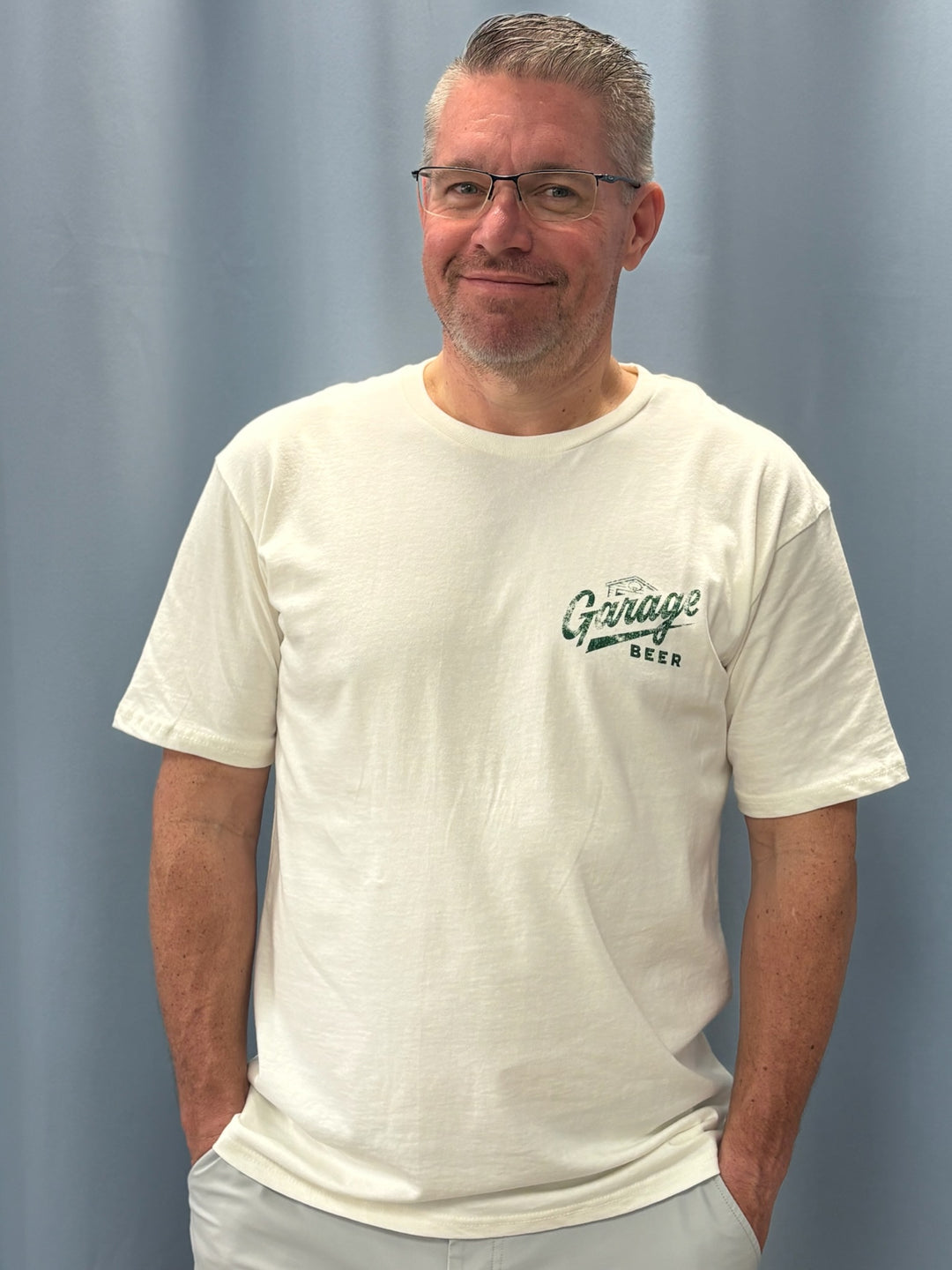 Man wearing a white t-shirt with a logo against a plain background