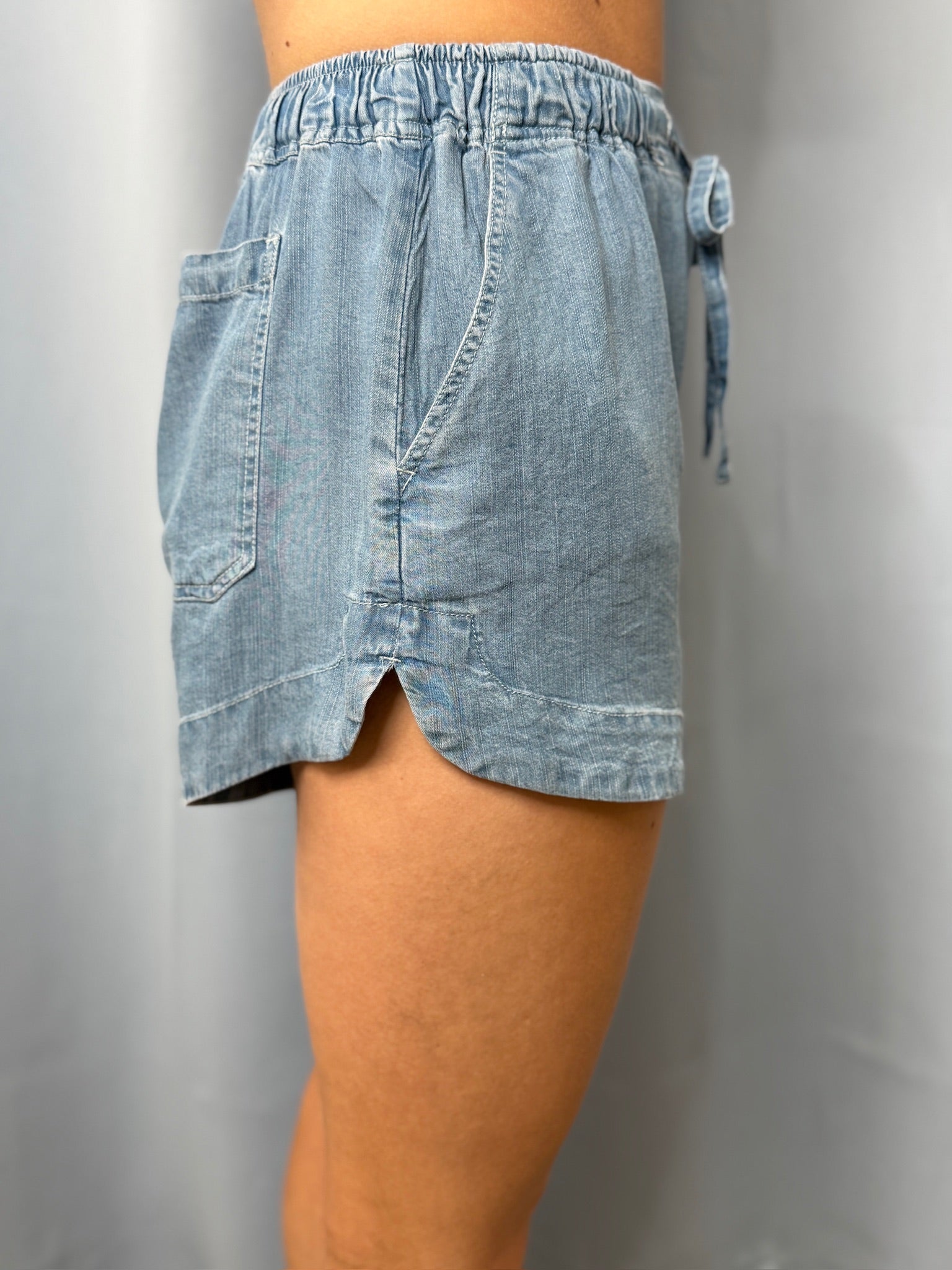 Light blue denim skirt worn by a person on a gray background