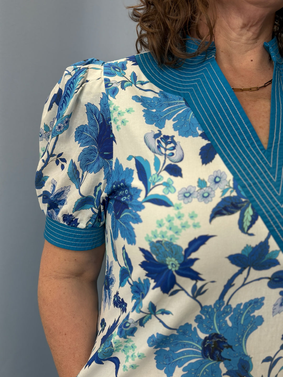 Woman wearing a blue floral blouse against a gray background