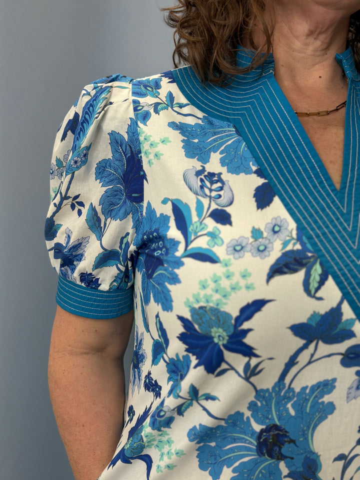 Woman wearing a blue floral blouse against a gray background