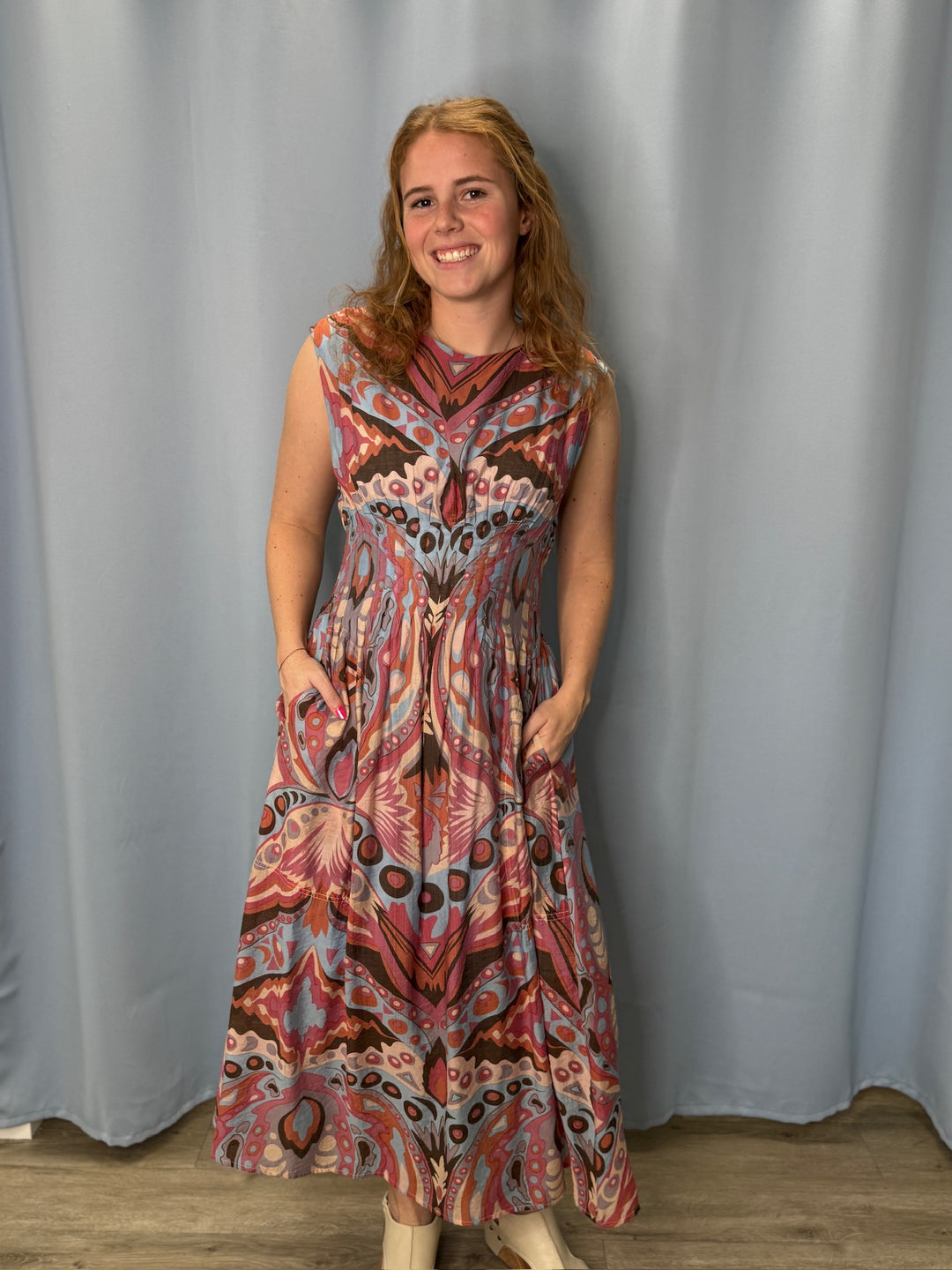 Woman wearing a patterned dress standing against a plain background