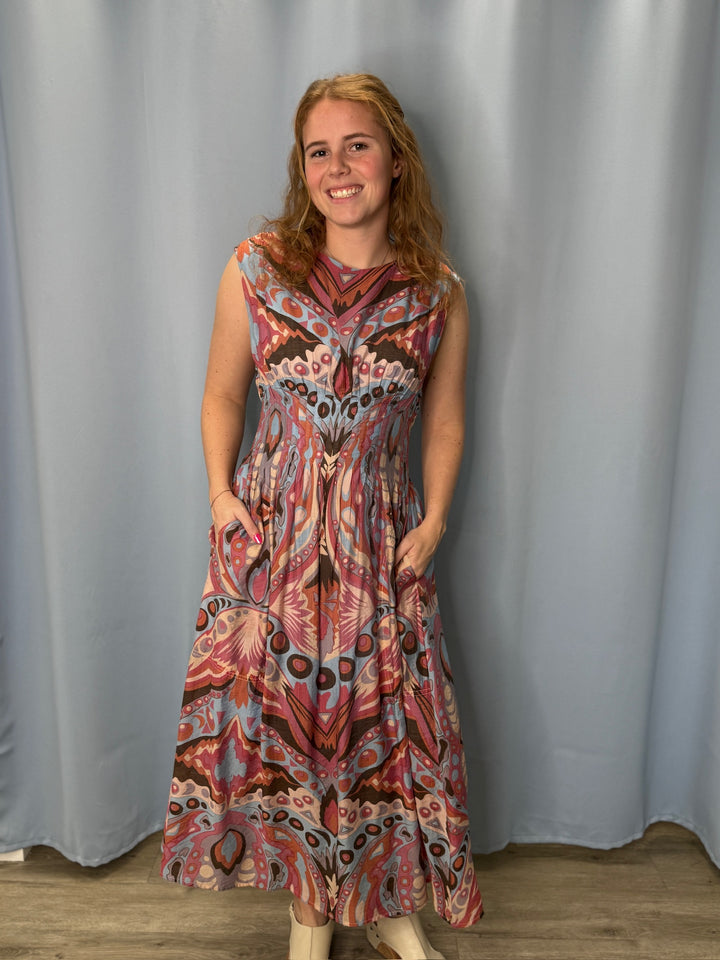 Woman wearing a patterned dress standing against a plain background