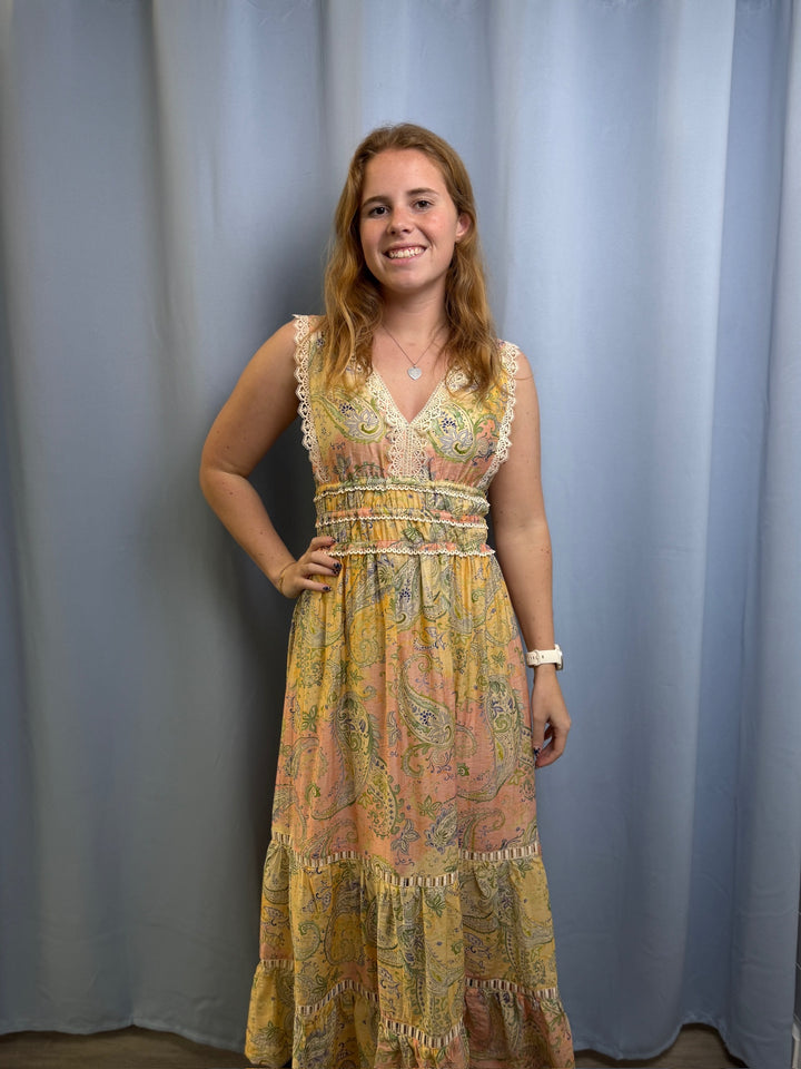Woman wearing a patterned dress standing against a plain background