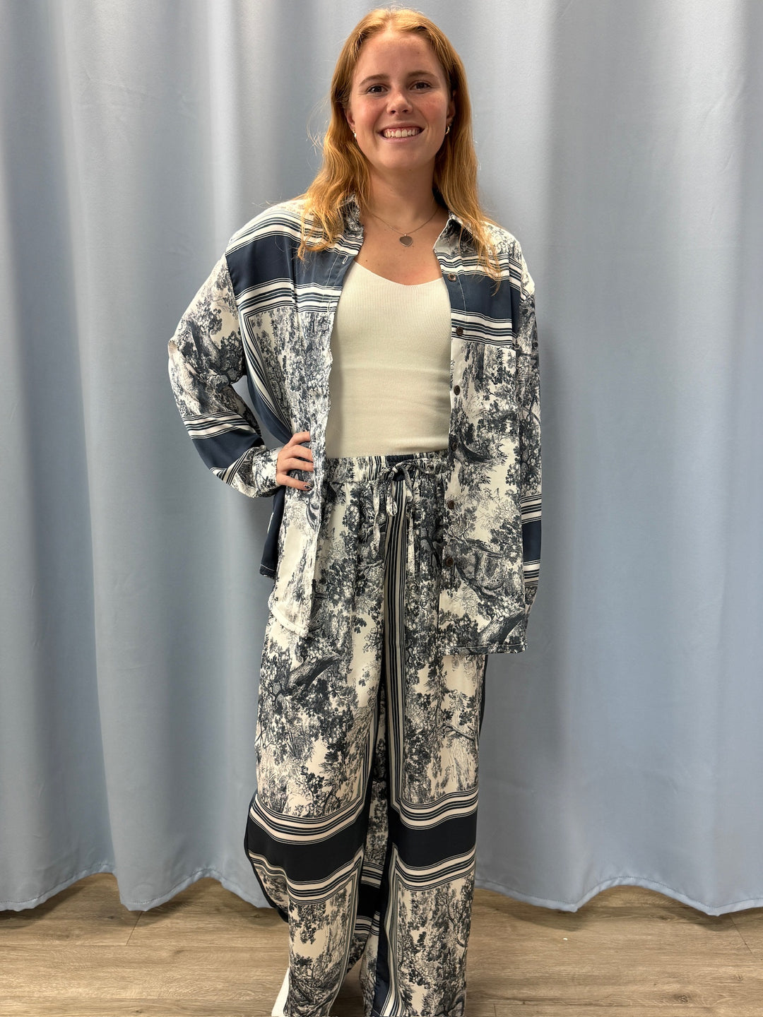 Woman wearing a patterned outfit standing against a plain background