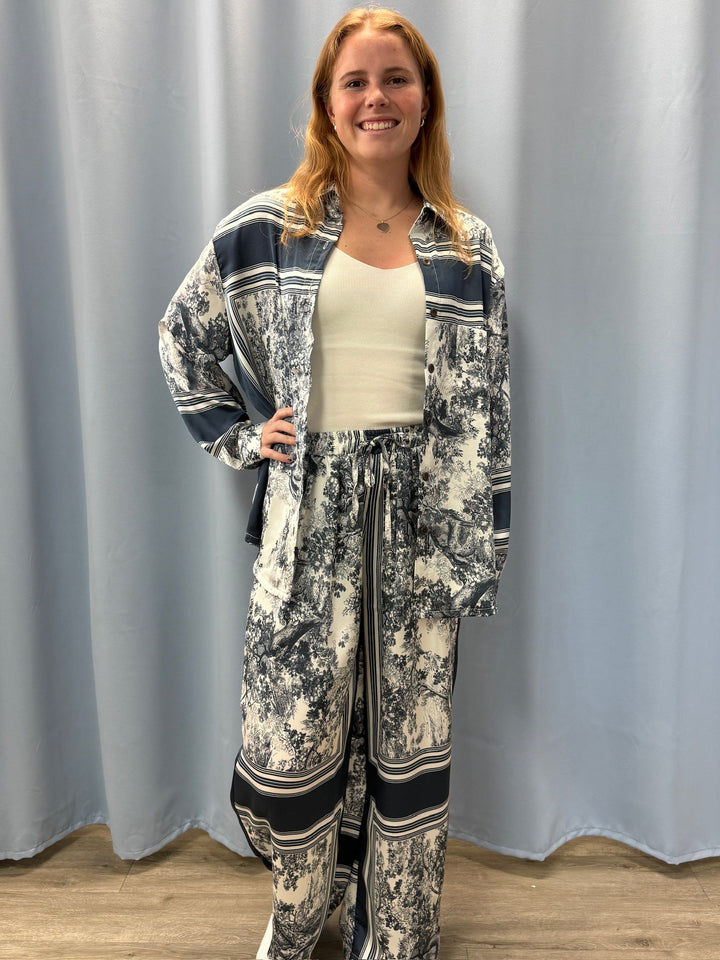 Woman wearing a patterned outfit standing against a plain background