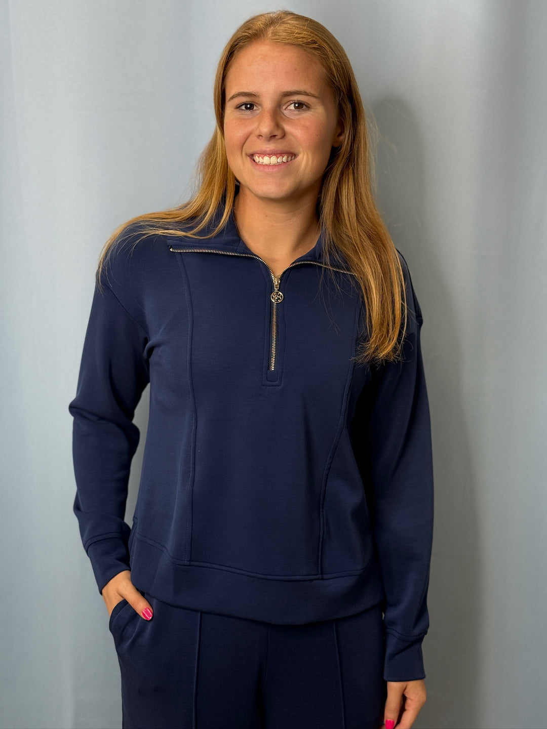 Woman wearing a navy blue outfit against a gray background
