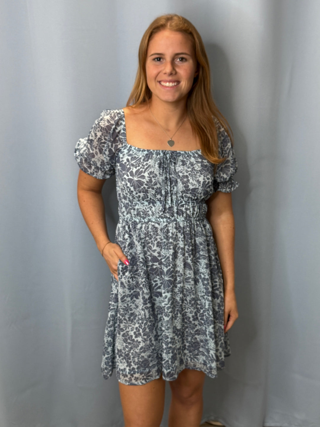 Woman wearing a floral dress against a plain background