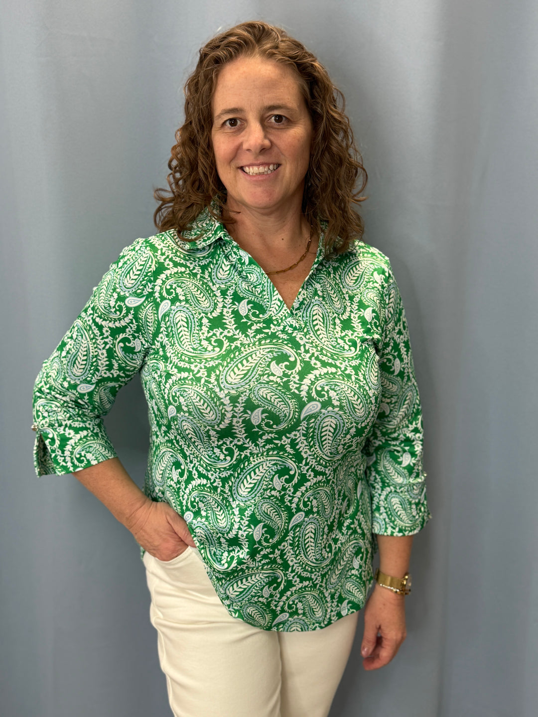 Woman wearing a green patterned blouse against a gray background