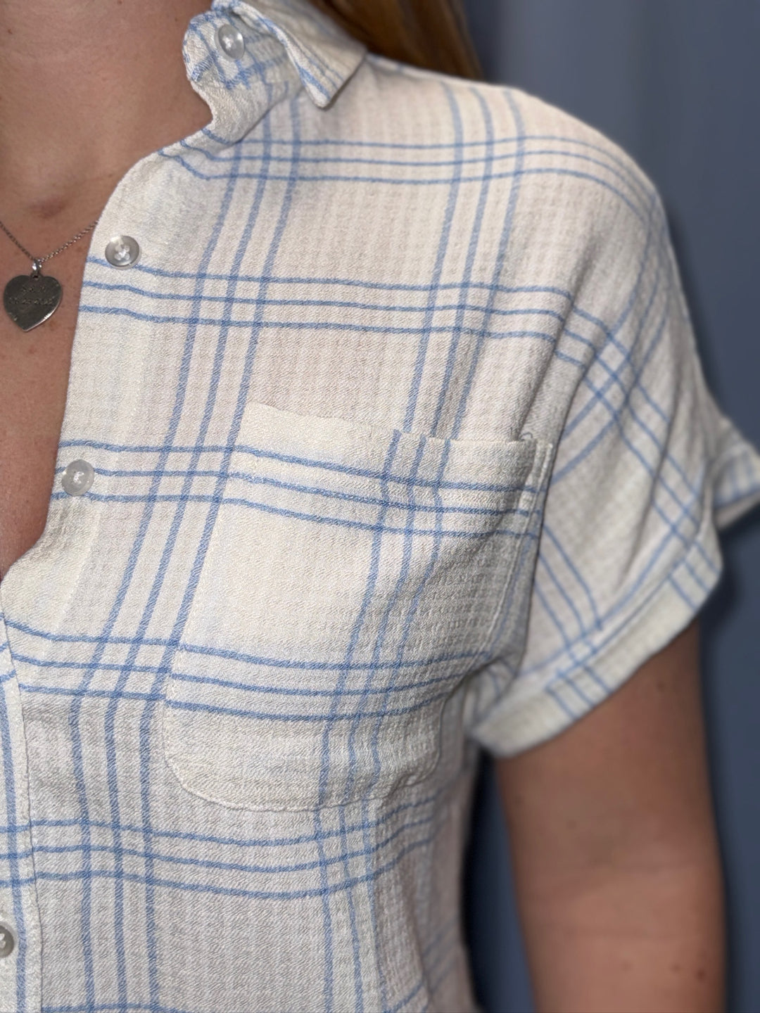 Close-up of a person wearing a blue and white checkered shirt with a plain background