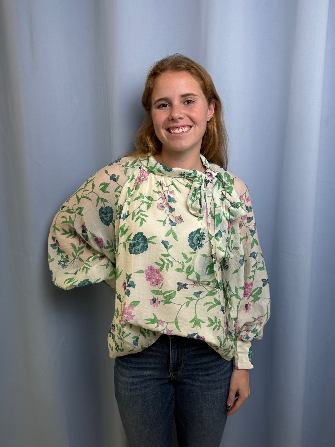 Woman wearing a floral blouse against a plain background