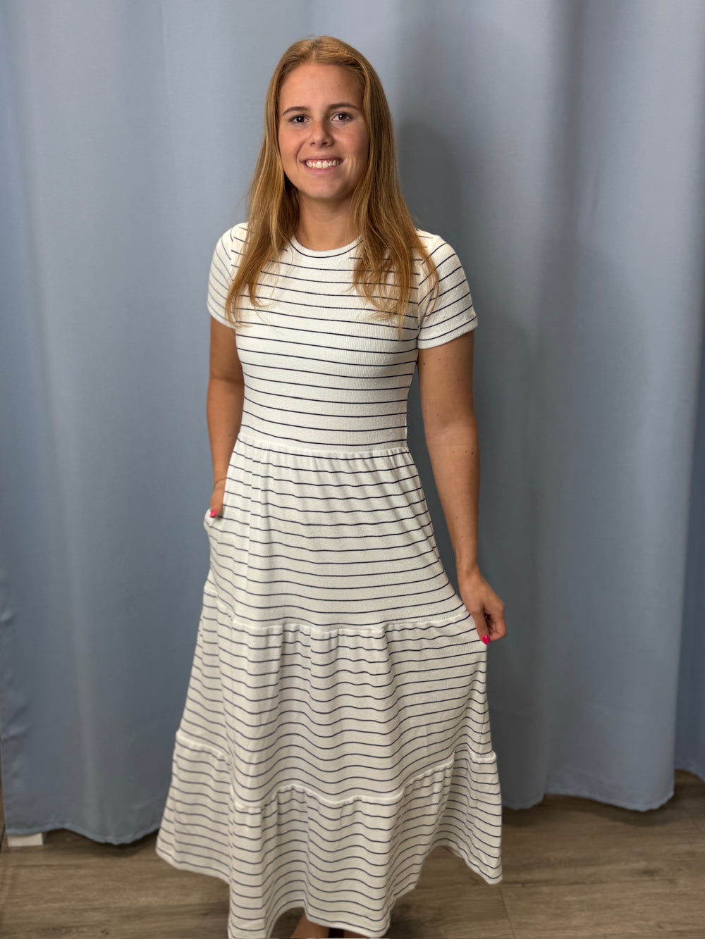 Woman wearing a white and black striped dress against a plain background