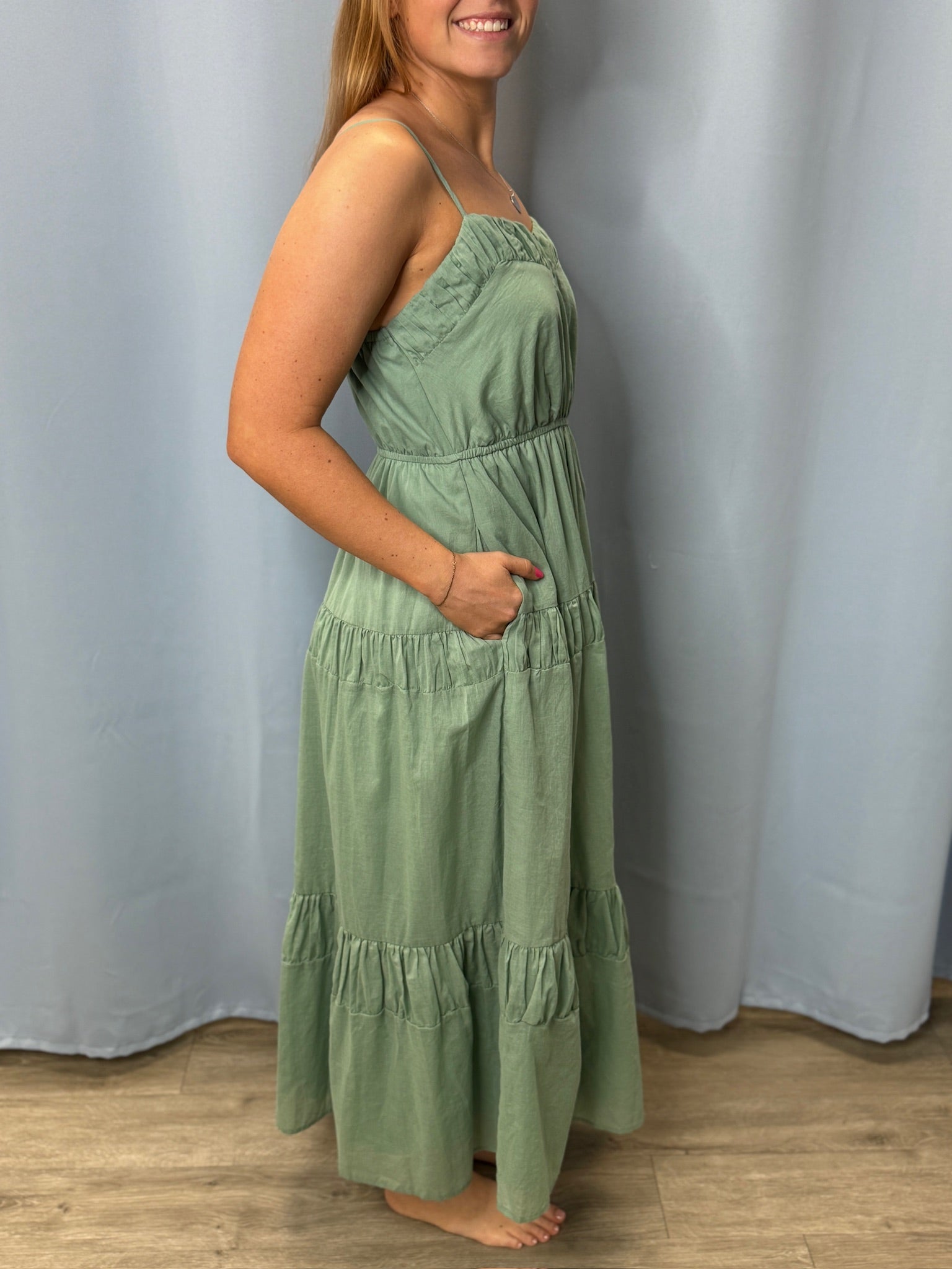 Woman wearing a green dress standing against a plain background