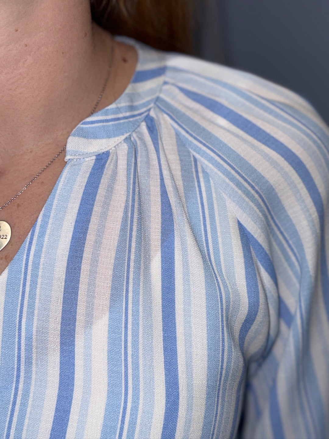 Close-up of a person wearing a blue and white striped shirt.