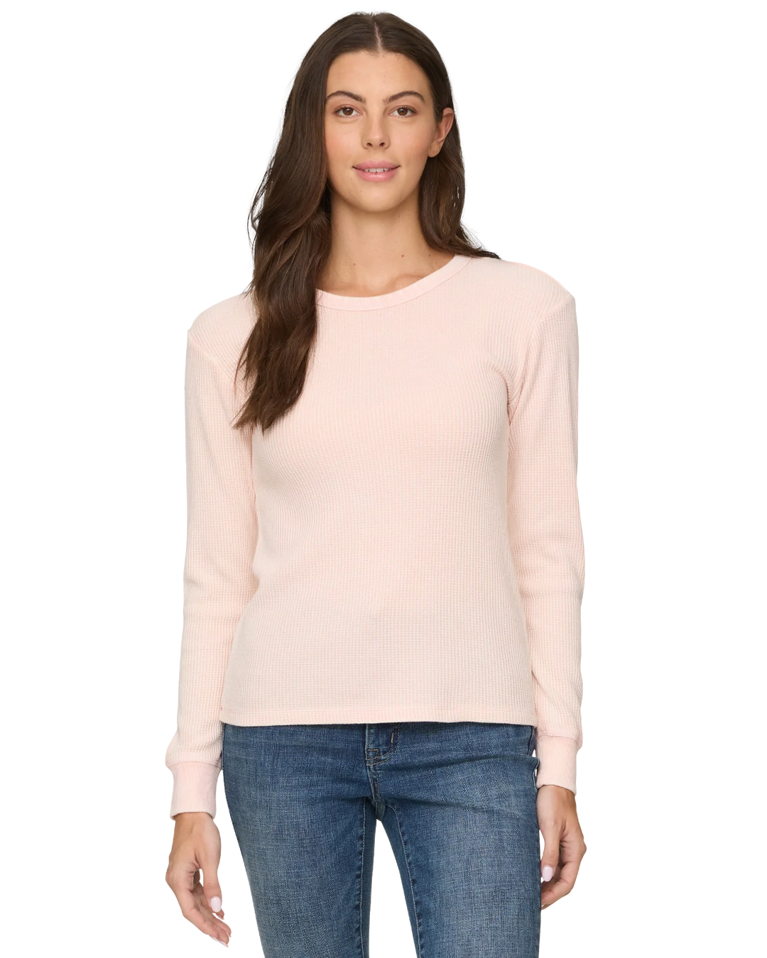Woman wearing a light pink sweater and blue jeans on a white background