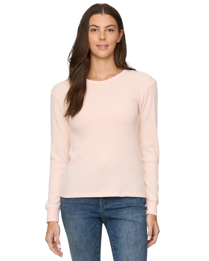 Woman wearing a light pink sweater and blue jeans on a white background