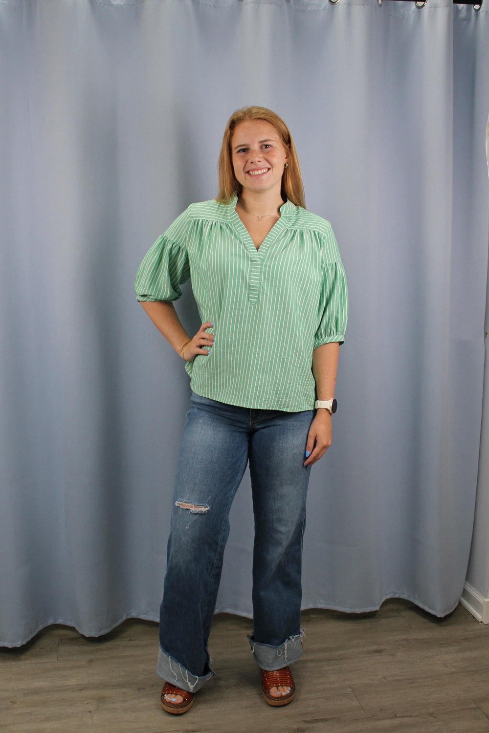 Woman standing in front of a large gray curtain indoors.