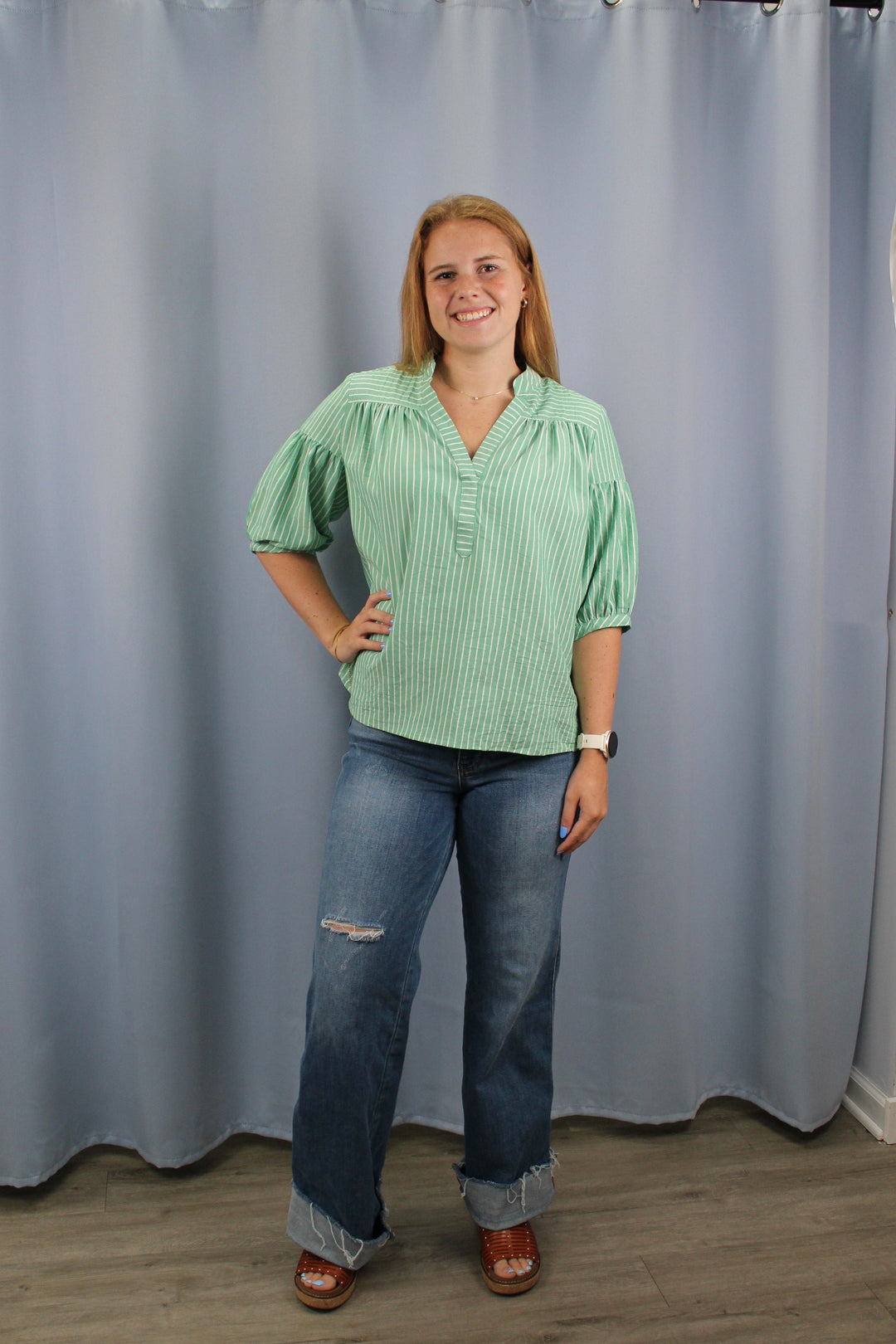 Woman standing in front of a large gray curtain indoors.