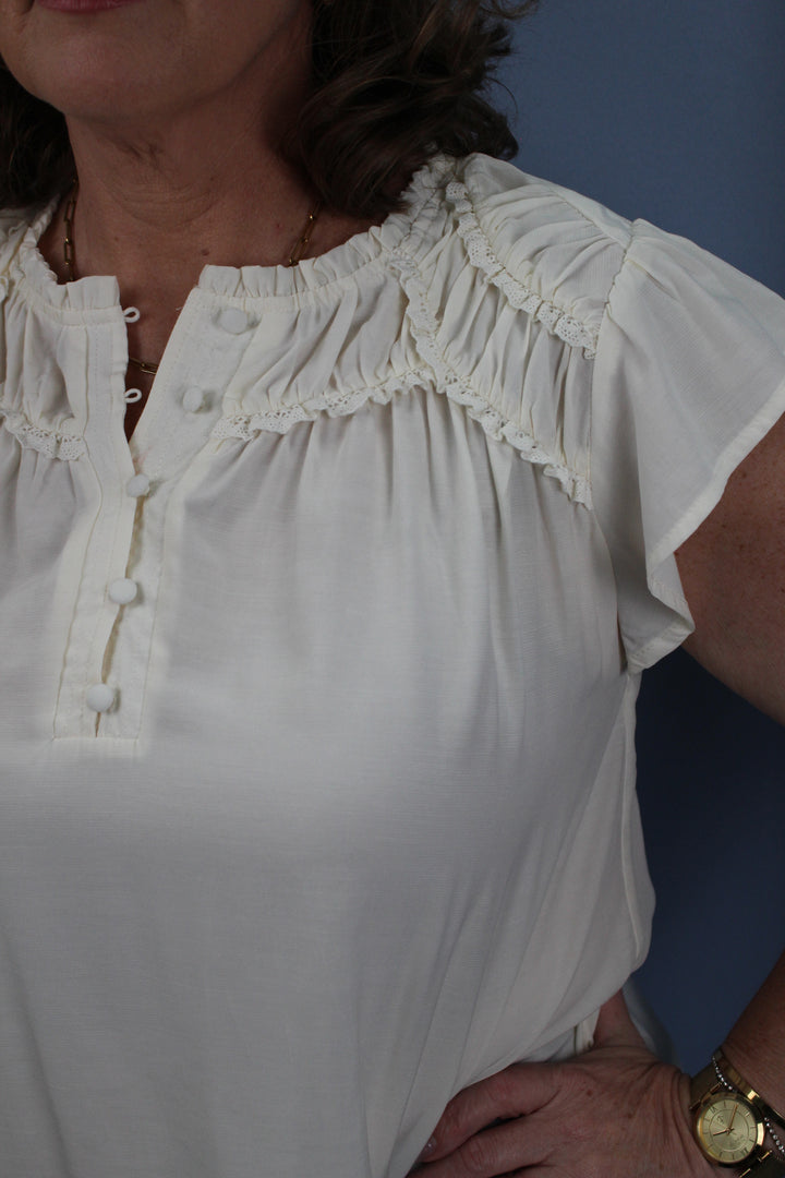 RUFFLED YOKE SHORT SLEEVE HENLEY BLOUSE